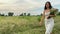 Rotating shot young pretty woman in dress enjoys strolling in field