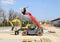 A rotating telehandler and an excavator at work for the construction of a  new parking lot.