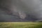 A rotating wall cloud hangs ominously under the base of a supercell thunderstorm.