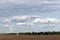 Rotating wind turbines at a distance in the field against the cloudy sky