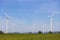 Rotating windmills on farmland against blue sky