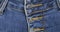 Rotation, close-up, detail of blue denim jeans, front view belt loop, pocket and button hole. Fashion background.