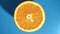 Rotation fresh appetizing orange circle half texture with seed and peel top view isolated on blue