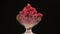 Rotation of a heap of red raspberries lying in a glass vase.