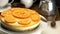 Rotation of homemade orange cheesecake garnished with cream and slices of oranges.