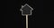 Rotation of the house-shaped sign. Wooden post with copy space in a frame on black background.