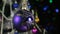 Rotation of a lilac Christmas ball and decorated Christmas tree, against the background of a blinking garland.