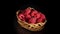 Rotation red raspberries in small wicker basket on black background.