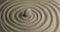 Rotation of the white stone in the center of the sand spiral. Close-up of patterns in the sand.