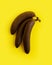 Rotten bananas on a yellow background. Darkened tropical fruit. Minimal composition of black bananas