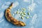 Rotten overripe banana with yellow pills on a blue background. health and pharmacology concept