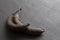 Rotten spoiled rotten fruits, bananas. Black bananas on a black dark background. Damaged products, mold. Still life fruit.