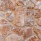 Rough brown stone wall close up, seamless textured background.