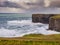 Rough cliffs of Kilkee, county Clare Ireland and powerful ocean. Irish nature landscape, Day time, cloudy sky. Popular travel and