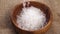Rough coarse sea salt falling in slow motion into a wooden rustic bowl on a burlap fabric