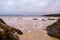 Rough coarse stone coastline and small patch of sand and powerful ocean wave. West coast of Ireland. Atlantic ocean. Irish nature