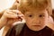 Rough fringe cut. Little child given haircut. Small child in hairdressing salon. Little boy with blond hair at