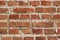 Rough rough red brick wall close-up. Texture of a red wall with a cement seam.