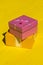 Rough shadow. Bright sunshine. Retro yellow wooden background. Gift box in pink