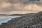 Rough stone beach at dusk, dark dramatic sky with sun light beams, Strandhill town, county Sligo, Ireland, Atlantic ocean. Rescue