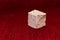 Rough stone cube isolated on blurred red background