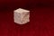 Rough stone cube isolated on blurred red background