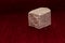 Rough stone cube isolated on blurred red background