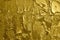 Rough texture of the old weathered cracked peeling golden graffiti paint on concrete wall. Vintage gold background.