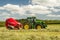 A round baler pulled by a John Deere during harvesting