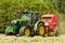 A round baler pulled by a John Deere during harvesting