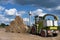 Round bales of hay with combine harvesters, summer day and blue sky in the background