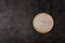 Round beige ceramic plate on dark structural background, top view