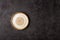 Round beige ceramic plate on dark structural background, top view