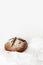 Round black bread lies on crumpled white paper on a white background. Space for text, daylight.