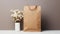 a round blank sticker mockup placed on a kraft paper gift bag adorned with delicate white flowers, the adhesive thank
