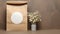 a round blank sticker mockup placed on a kraft paper gift bag adorned with delicate white flowers, the adhesive thank