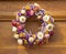 A round bouquet of colorful, vibrant dried flowers on an old wooden door. Autumn decoration