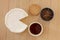 Round brie cheese with cup of tea, biscuit and tea leaves in a bowl on wooden background. Top view modern minimalistic image