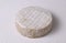 Round Brie cheese with a sections cut out over white corrugated background