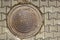 Round brown rusty sewer manhole in gray paving stones with checkered pattern. rough surface texture