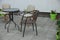 Round brown table with chairs stand on the gray sidewalk