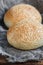 Round bun, sesame bun, bread rolls. Tasty burger bread with sesame on wooden, burlap background. Freshly baked hamburger buns. Top