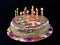 Round cake with candles, on a black background. A sweet birthday present for a teenager. A festive dessert for the whole family