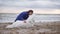 Round camera movement: young woman sitting on the sand and embracing her dog of the Samoyed breed by the sea. White