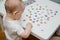 Round cards with pictures are laid out on a white table. The kid is studying pictures with different objects and animals on the