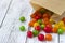 Round colored candy in a paper bag on a wooden table, bright sweets, background