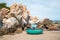 Round colourful Vietnamese fishing boat stands on the beach with large rocks.