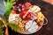 Round cutting board with slicing assorted cheese, sausage rosette, ham, cracker, grapes and figs with honey