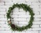 Round elegant Christmas wreath hanging on white brick wall