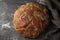 Round, freshly baked rye flour bread, on a gray background,